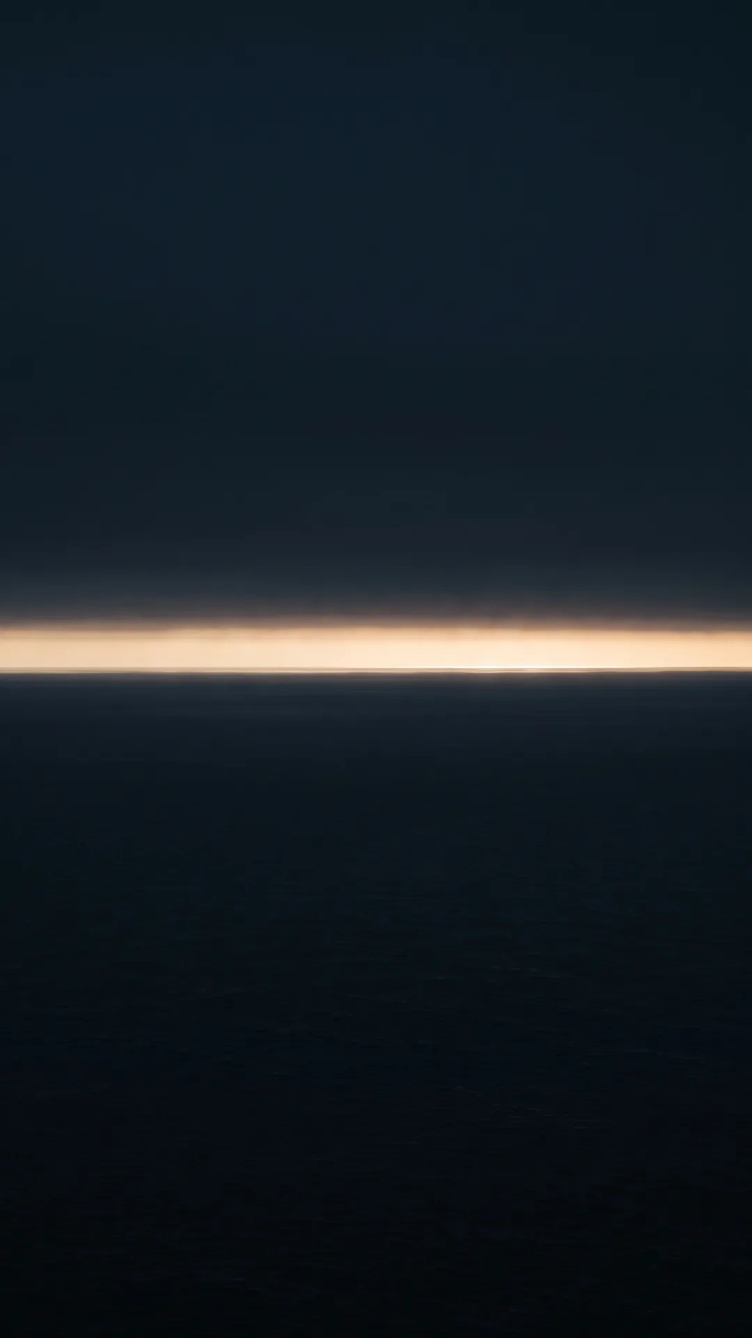 A thin band of warm light on the Mediterranean horizon between dark sea and sky