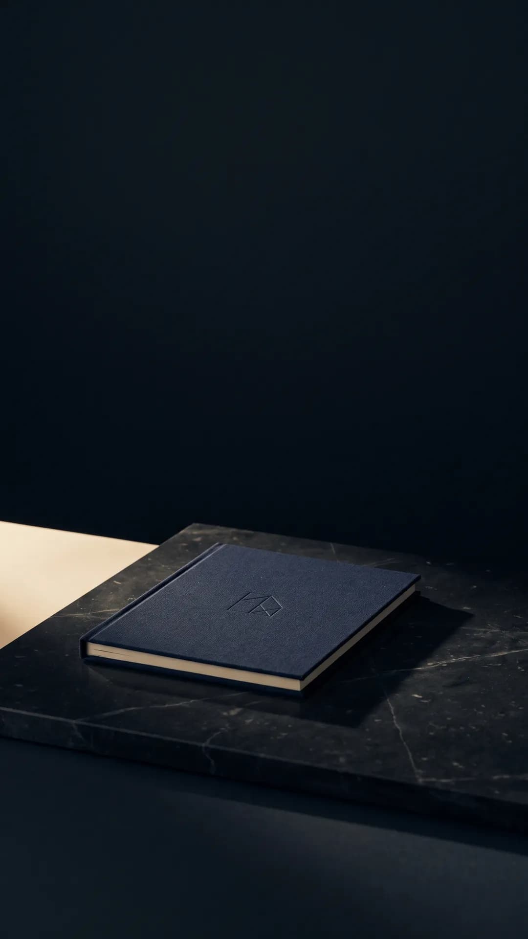 A navy linen booklet with a blind-embossed mark on dark marble