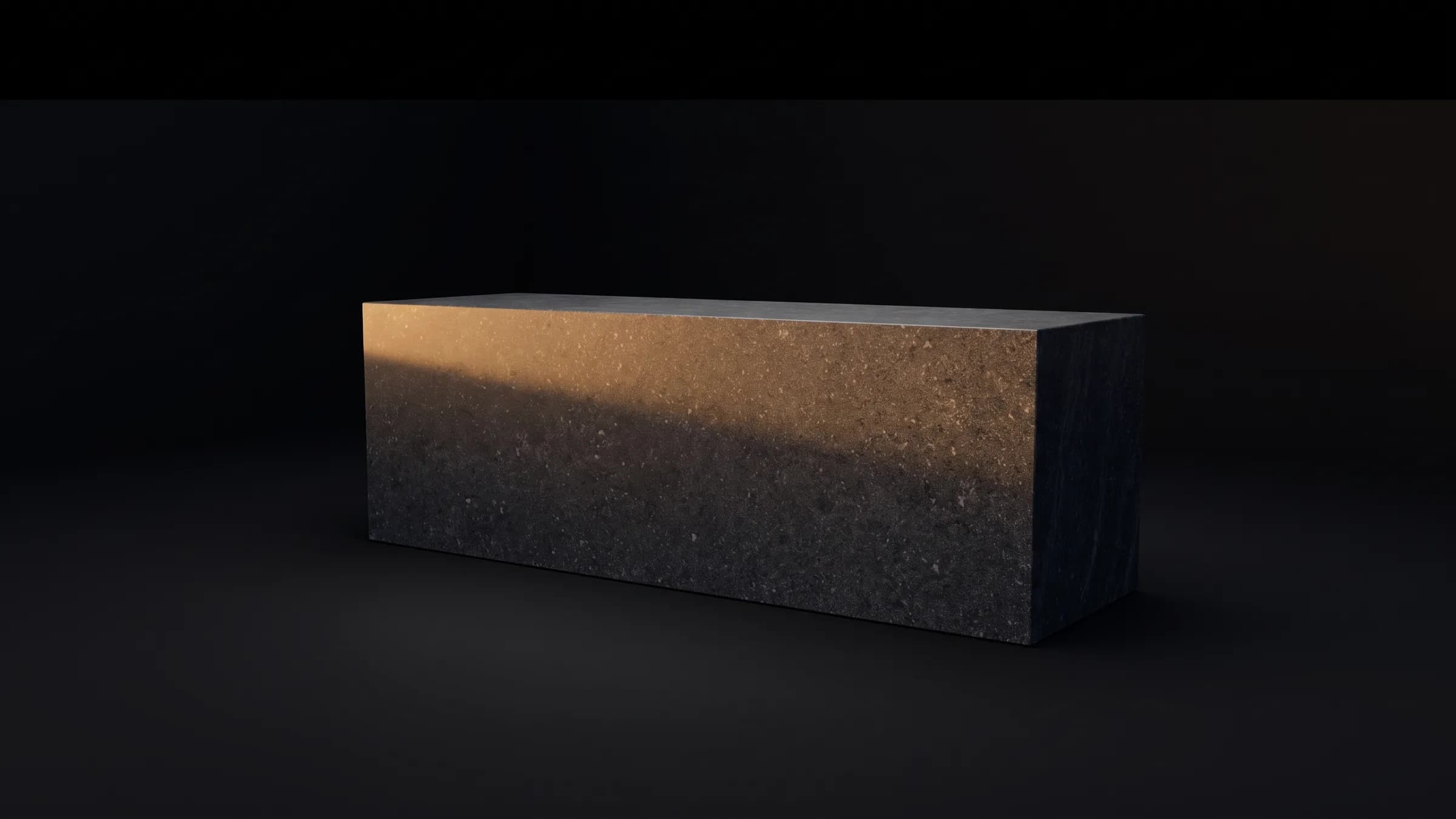 A monolithic block of honed dark stone in warm dusk light